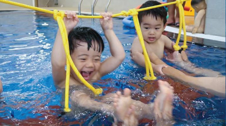 2.5-3.5歲幼兒使用特殊教具 (Aquamoov) 進行繩索抓握與平衡練習，在遊戲中強化上肢肌力與核心穩定度，將體適能融入游泳教學。