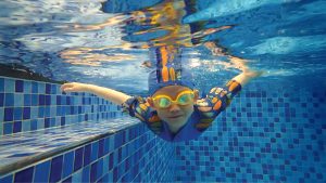 5-8歲兒童在水中自信展現泳姿，此階段課程專注於動作協調性與精確的換氣技巧，為學習標準四式游泳打下穩固基礎。