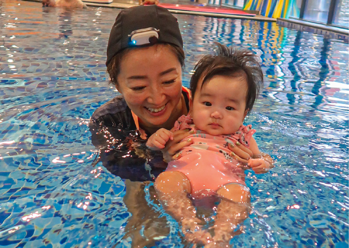 媽媽在水中溫柔扶持寶寶，透過近距離的眼神交流與笑容，強化寶寶的水中安全感並建立正向的游泳學習經驗。