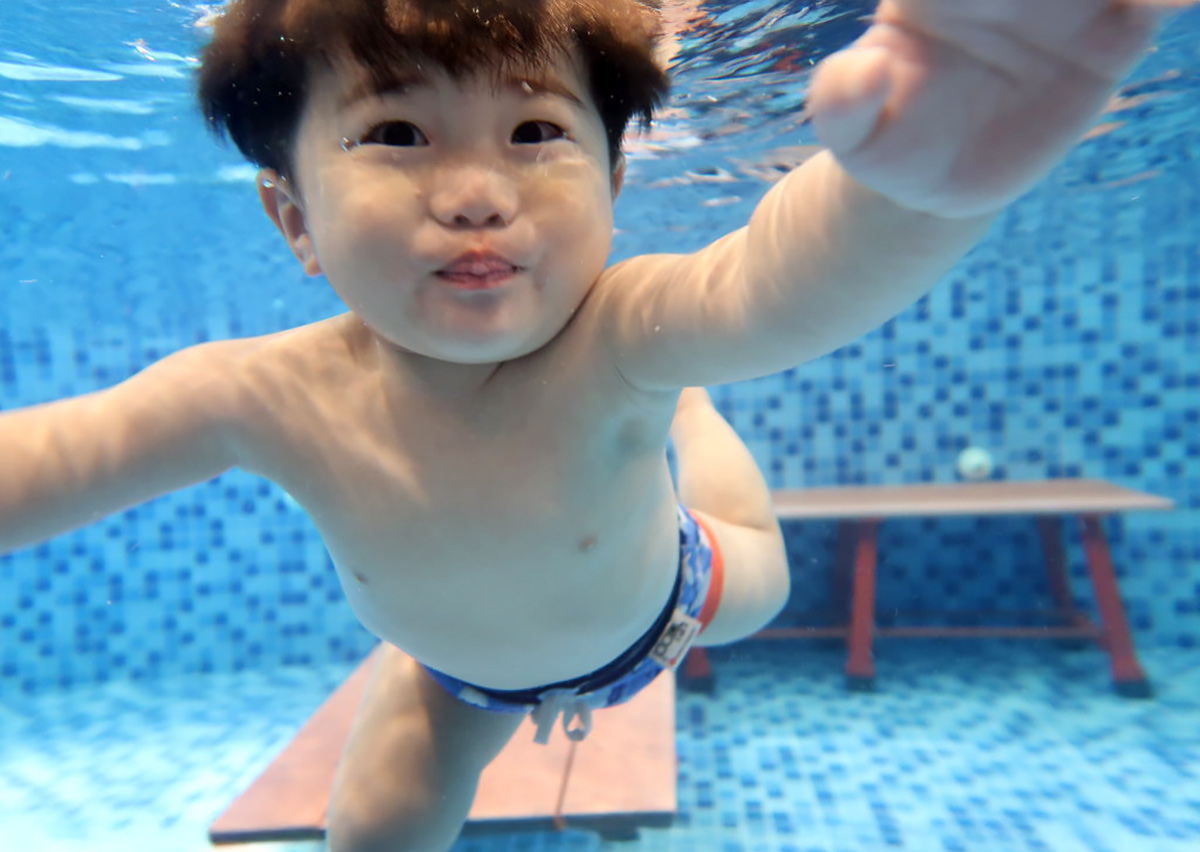 幼兒在水中自信潛水並睜開眼睛面對鏡頭，展示熟練的閉氣反射 (Breath Control)