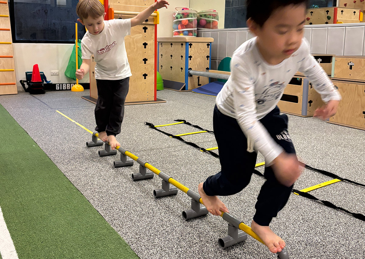 兒童專注地在圓形管狀器材上行走，這項高難度的動態平衡練習能訓練腳底本體感覺 (Proprioception)，並極大化提升孩子的專注力與身體協調性。