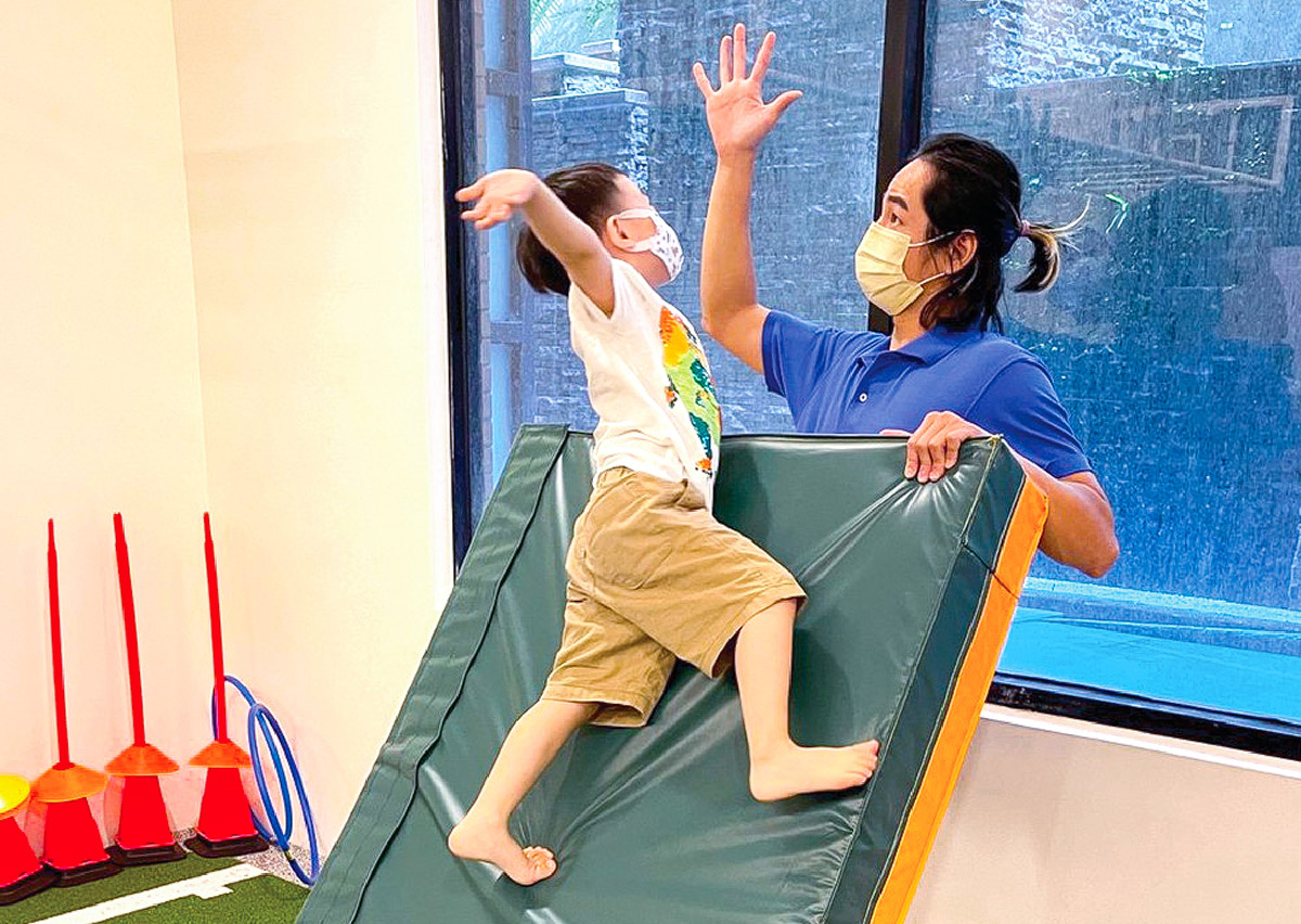 幼兒成功攀爬斜坡軟墊後與教練擊掌 (High Five)，透過正向強化 (Positive Reinforcement) 建立孩子的運動自信與成就感，鼓勵主動挑戰自我。