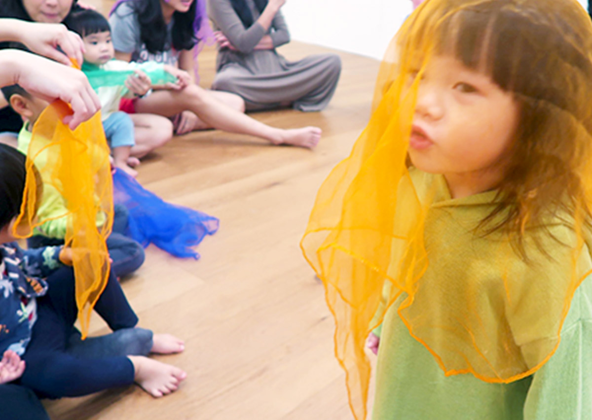 孩子們在教練引導下玩絲巾遊戲，透過觀察絲巾緩慢飄落的路徑，訓練眼球的視覺追蹤 (Visual Tracking) 能力與專注力，屬於靜態的感統訓練。