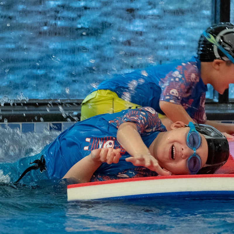 兒童在不穩定的水上浮墊上翻滾與移動，這項活動旨在訓練動態平衡 (Dynamic Balance) 與本體感覺，讓身體適應水波晃動，增進水中控制能力。