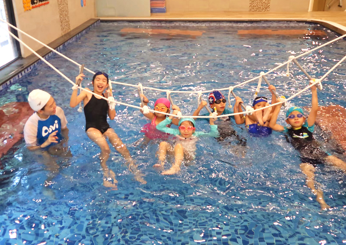 兒童挑戰水上繩索攀爬架，這項結合體適能 (Physical Fitness) 的游泳課程能強化孩子的上肢握力與核心肌群，並培養面對挑戰的冒險精神。