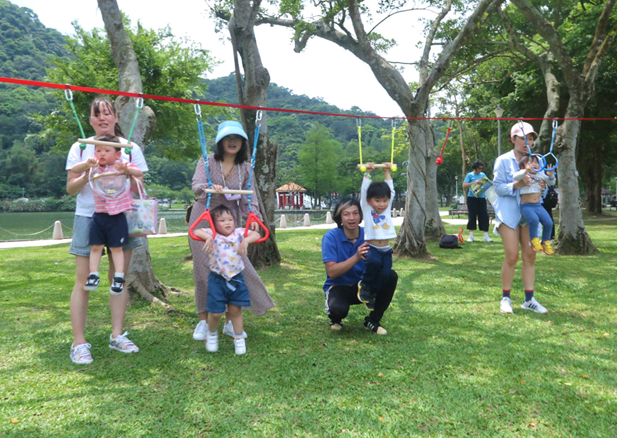 孩子們在戶外樹林間挑戰繩索懸吊設施，這項冒險活動能大幅強化上肢肌力與手部握力 (Grip Strength)，並滿足孩子對擺盪與攀爬的感覺統合需求。