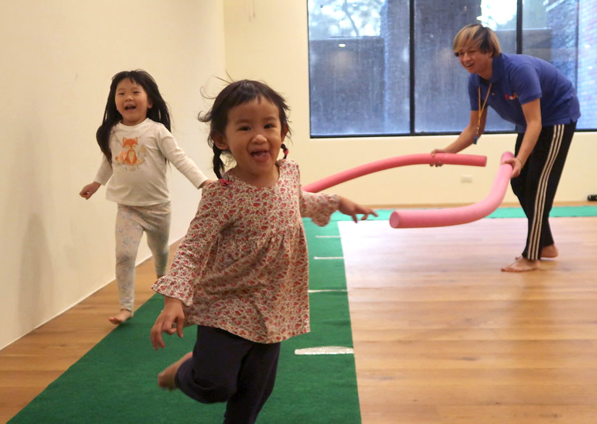 孩子們在室內體能教室快樂奔跑穿越障礙，訓練基礎的位移技巧 (Locomotor Skills) 與視覺反應速度，在充滿樂趣的氛圍中提升心肺耐力。