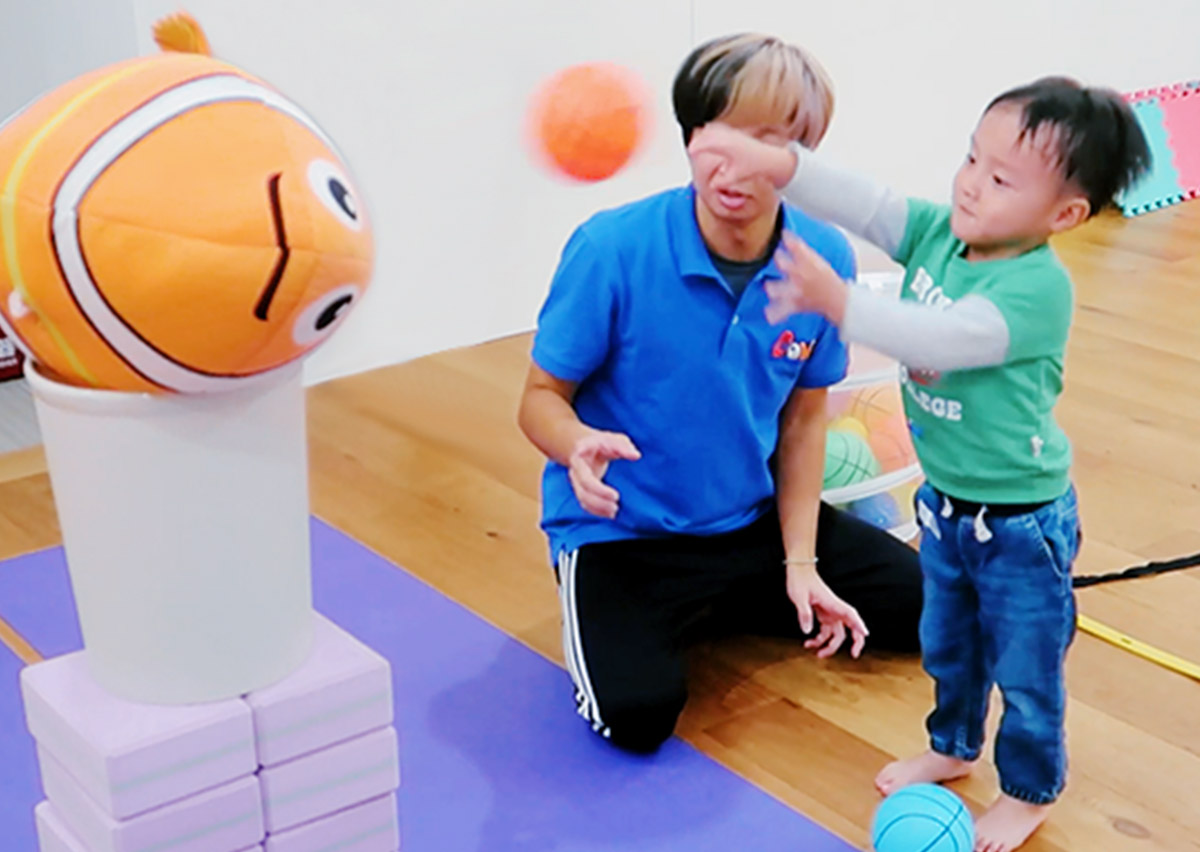 幼兒練習將球投向尼莫玩偶目標，透過遊戲化教學引導孩子學習正確的上肢投擲姿勢，為未來學習複雜球類運動打下良好的協調基礎。