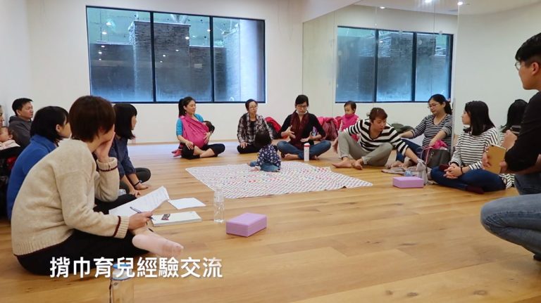 家長們圍坐一圈進行「揹巾育兒經驗交流」。這類非正式教育場域能有效降低育兒焦慮，體現 Oovi 課程強調「以人為本」與「家長賦權」的核心價值。