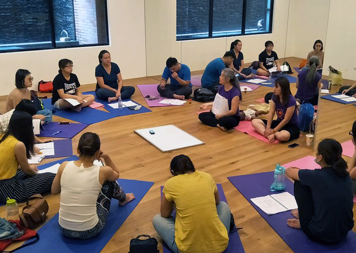 學員於 Oovi 教室進行理論講座，使用教具娃娃模擬水下抱法。這種沉浸式教學確保學員在下水前已完全掌握安全規範。