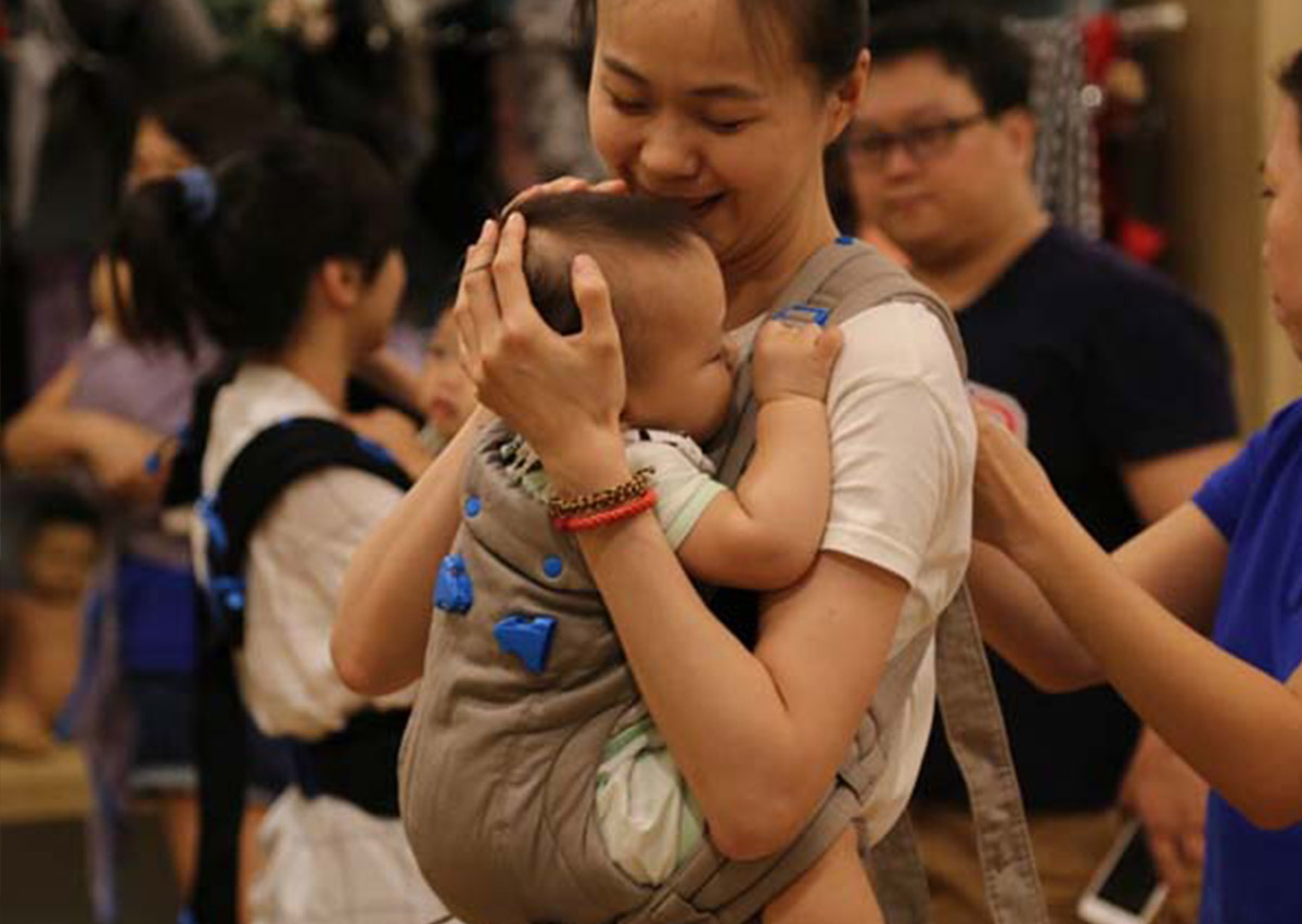 媽媽在揹巾中溫柔擁抱並親吻寶寶額頭，完美詮釋 T.I.C.K.S. 安全守則 中的「親吻距離」，強調揹巾穿戴不僅是工具，更是傳遞愛與親密育兒 (Attachment Parenting) 的橋樑。