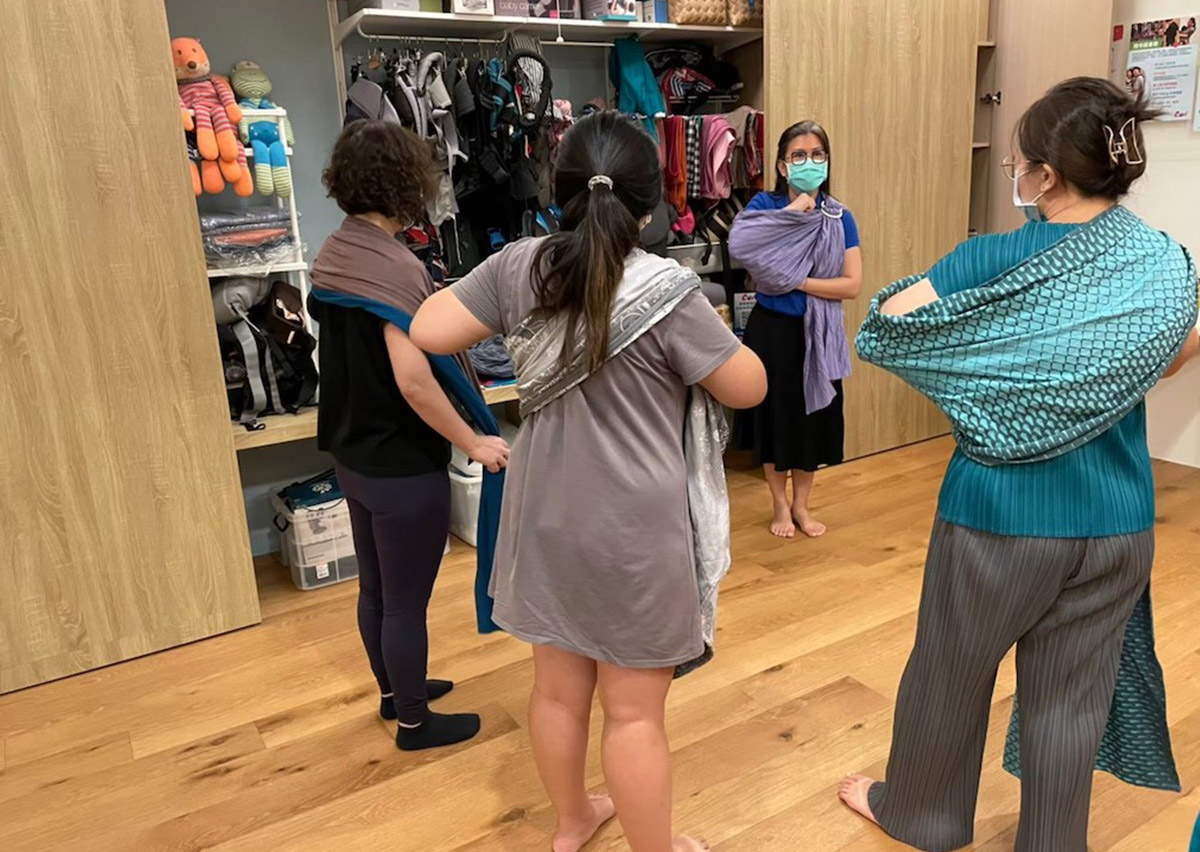 培訓學員使用教具娃娃練習長布揹巾 (Woven Wrap) 的多種進階揹法。透過反覆練習確保動作流暢度與安全性，符合 T.I.C.K.S. 國際安全穿戴準則。