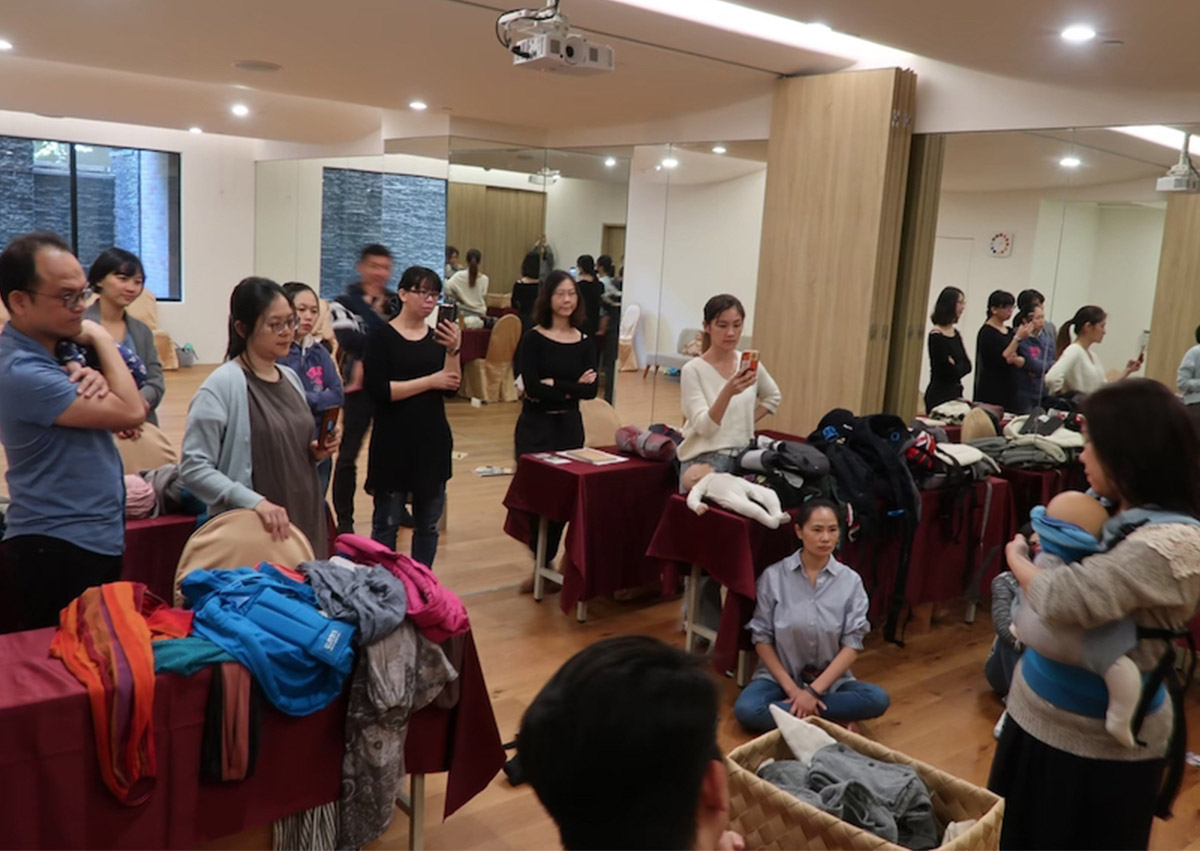 專業揹巾顧問培訓的理論教學現場，學員學習如何評估不同品牌（長布、環揹、SSC）的結構差異，建立客觀的育兒輔具推薦專業能力。