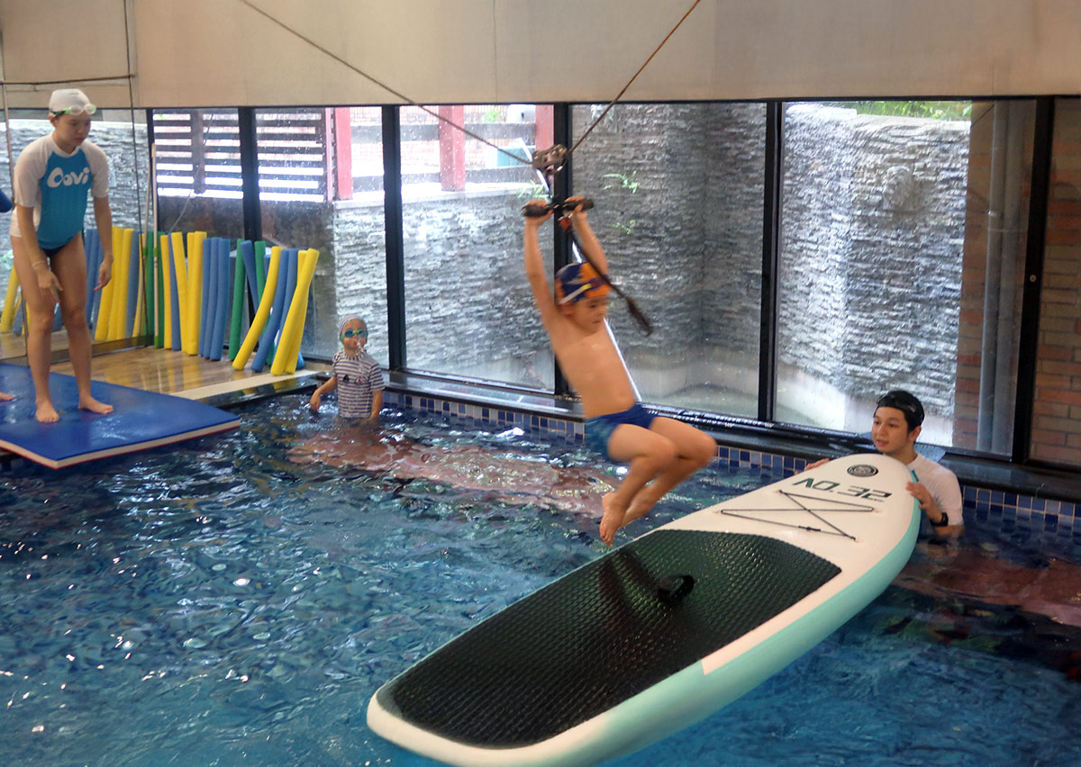 男童抓握飛索橫越泳池並降落於立槳板，極大化訓練孩子的膽識、抓握耐力與動態平衡控制。