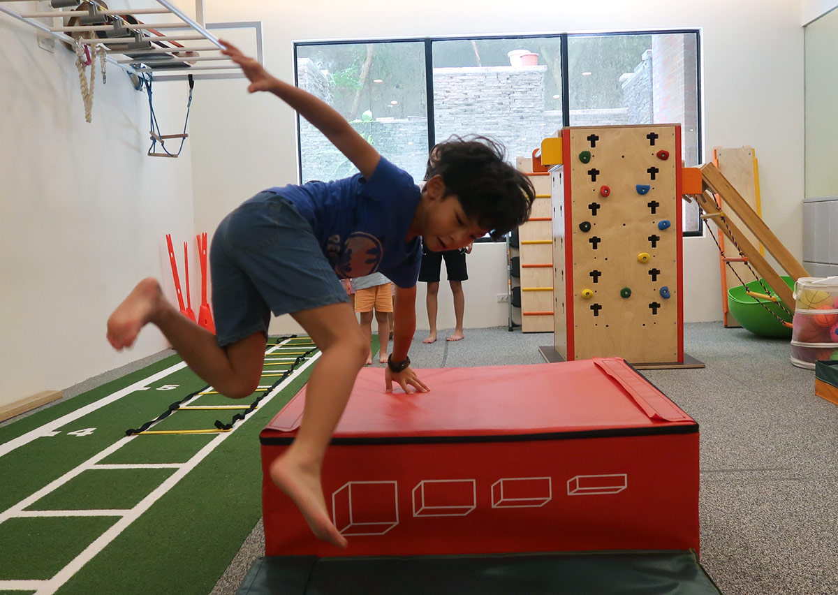 孩童練習單手撐跳過紅色軟墊箱，透過跳躍訓練發展爆發力，並學習安全的落地姿勢與重心轉移。