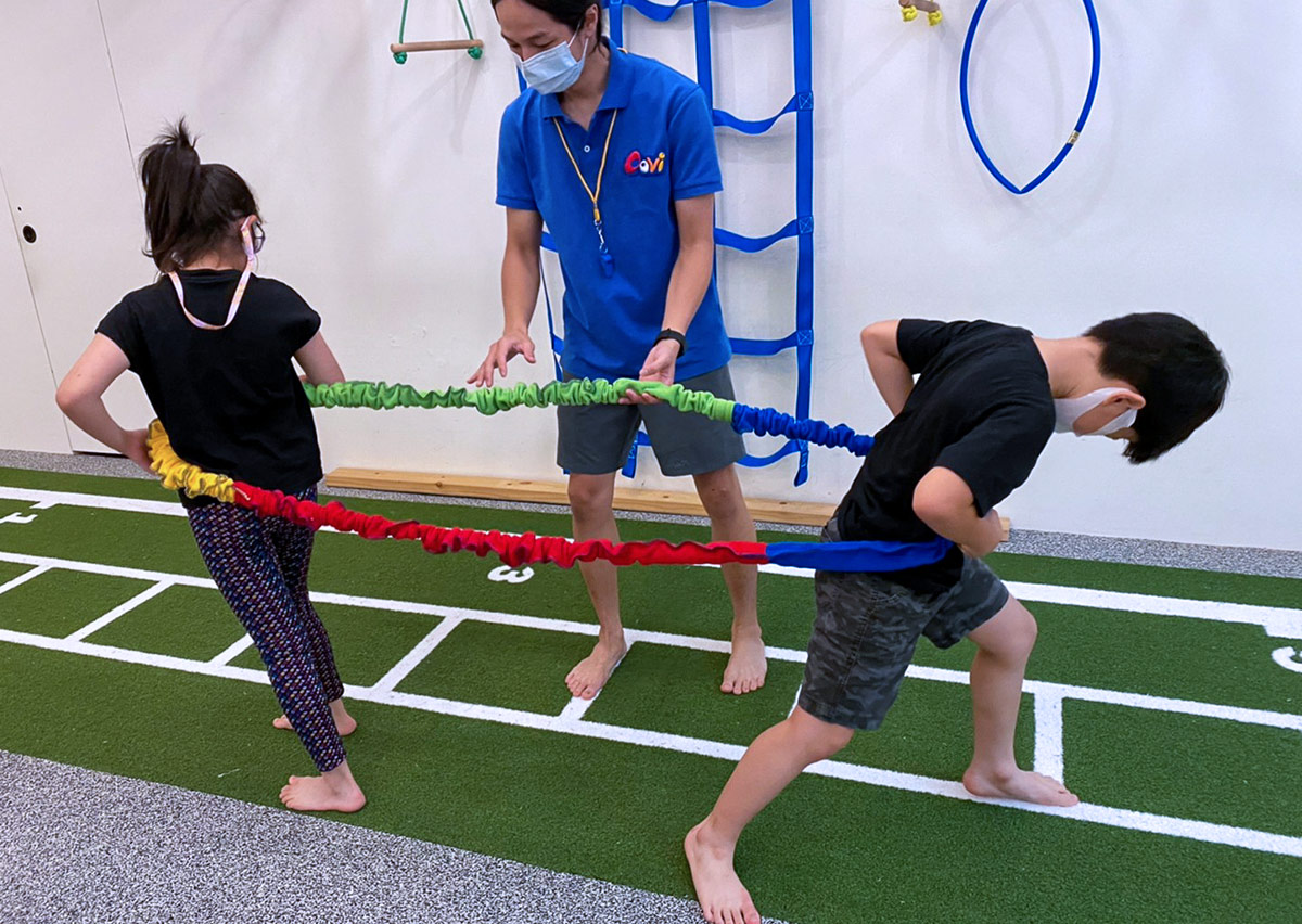 兩名學員在 Oovi 教練指導下利用彈力帶進行阻力對抗遊戲，透過力量訓練提升腿部推力與身體穩定度。