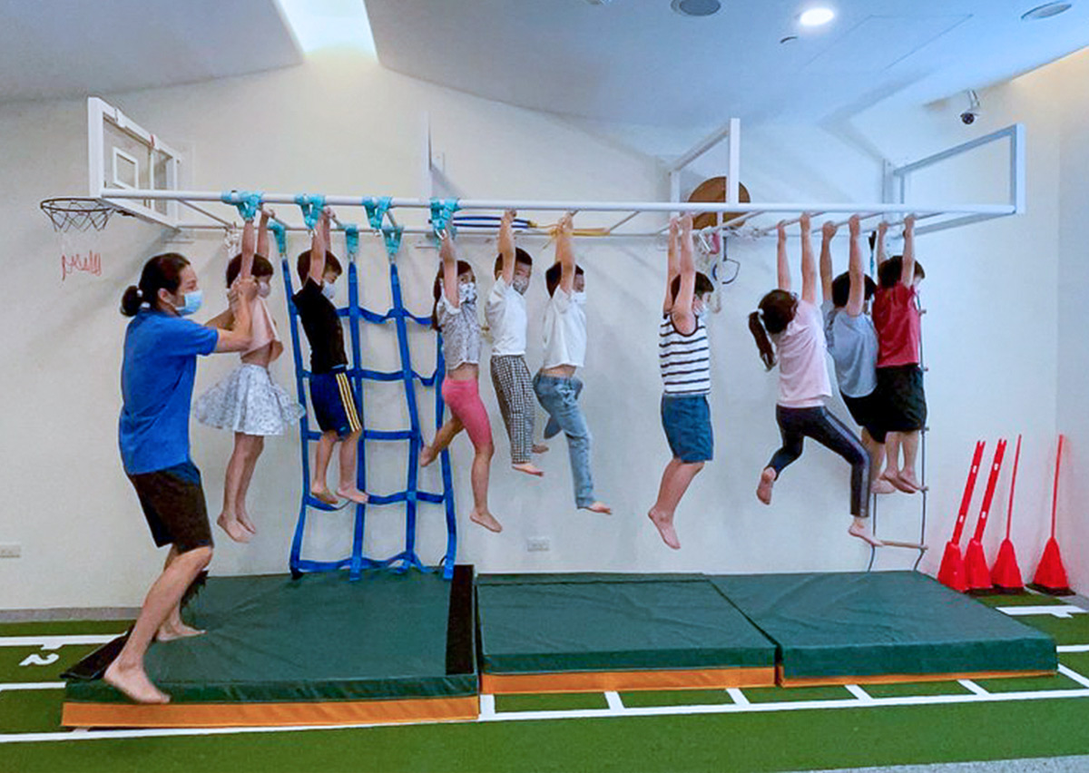 一群孩子在 Oovi 主題營隊中集體練習猴架懸吊前行，在挑戰過程中強化握力、勇氣與同儕間的激勵。