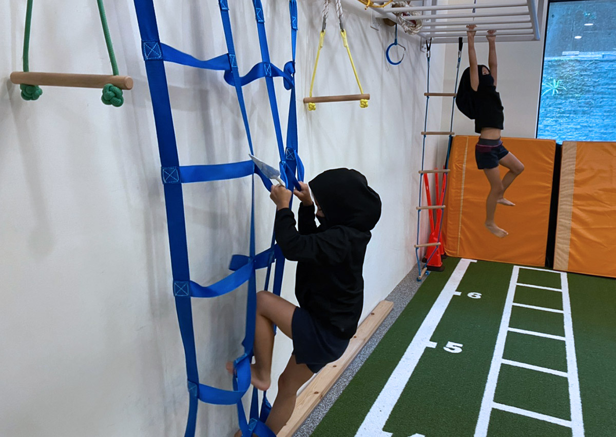 Oovi 小忍者主題營隊學員，穿著自己DIY的忍者裝，在室內挑戰藍色繩網設施，透過手腳並用的攀爬過程強化抓握力、身體協調性與克服高度障礙的心理素質。