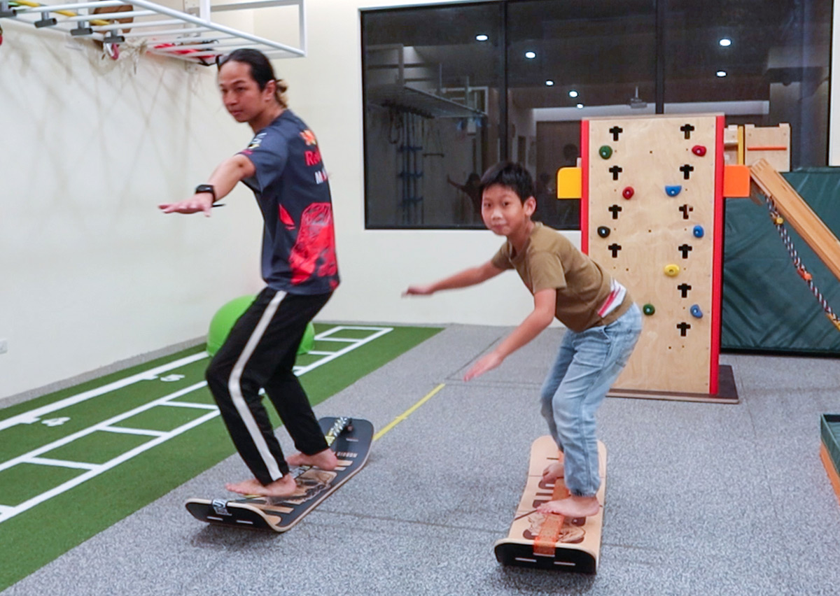 教練引導學童在室內教室練習平衡板，透過重心位移訓練強化核心肌群、專注力及手眼協調性。