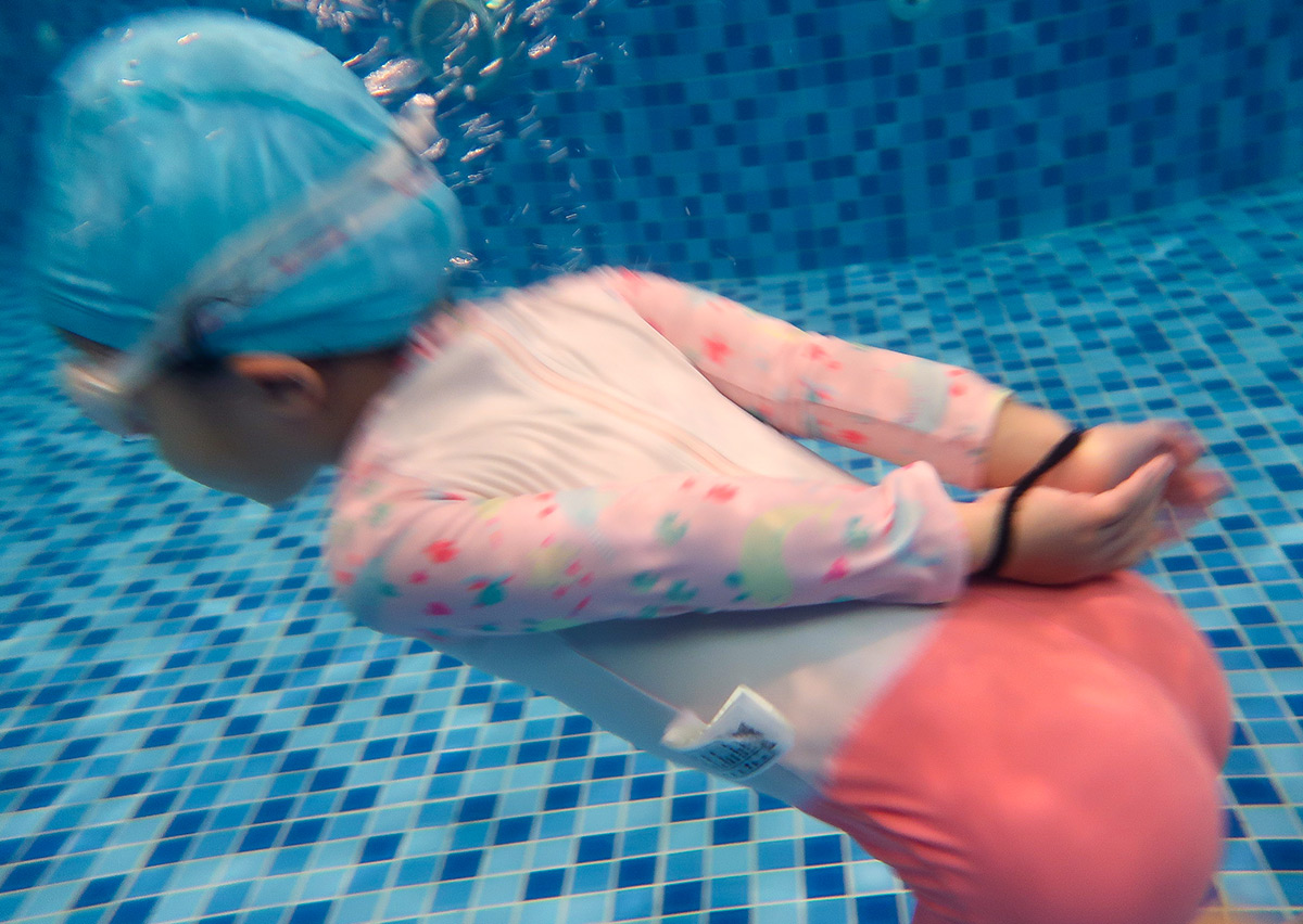 在專業防溺課程中，孩童練習在雙手受束縛的模擬情境下，如何運用身體核心與腿部力量維持水中求生，展現高階水域安全自救經驗。