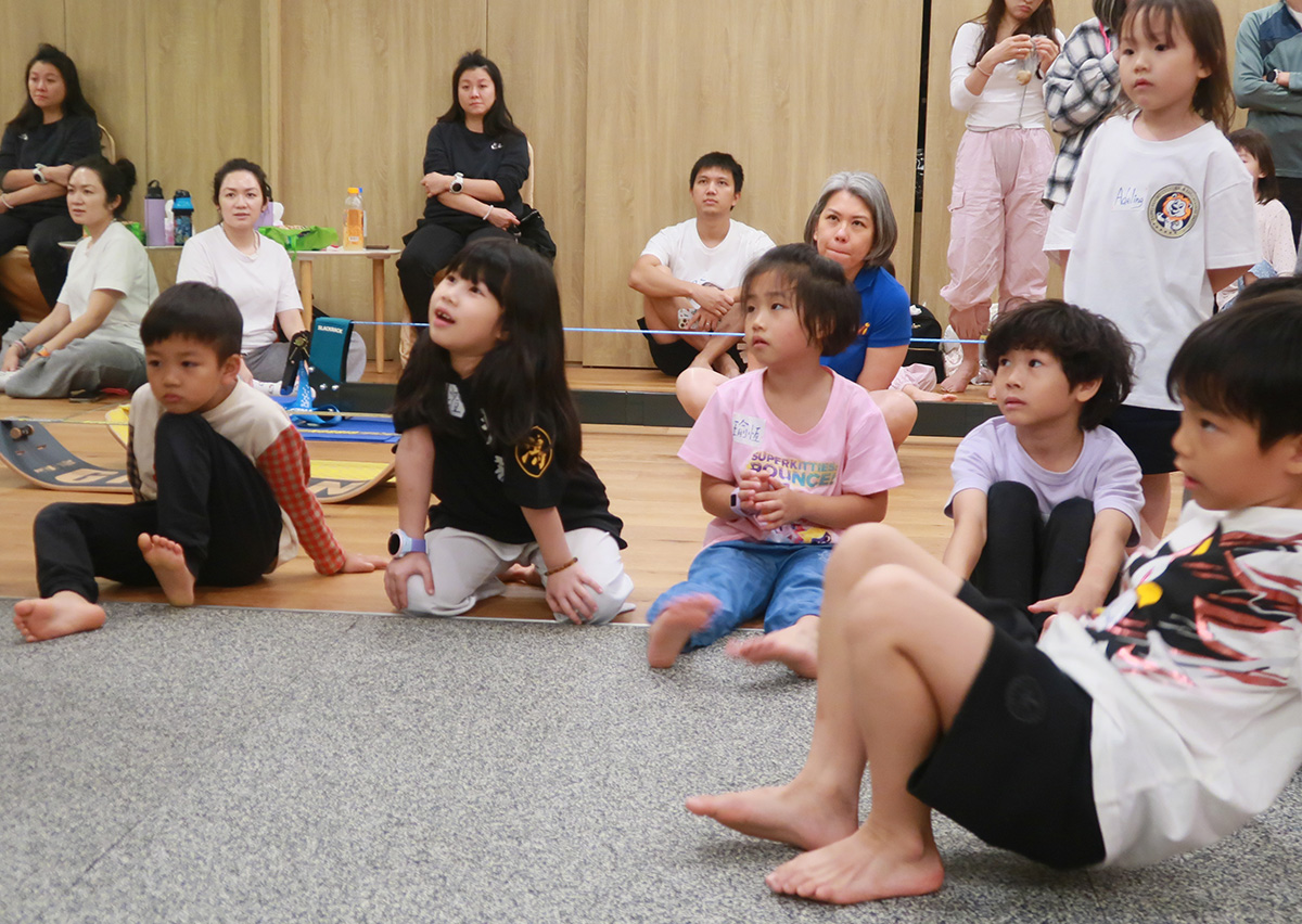 兒童在 Oovi 挑戰賽活動中專注聆聽教練解說規則,展示團體紀律與專注力 (Attention) 訓練,這是運動學習中重要的心理素質與聆聽技巧培養。