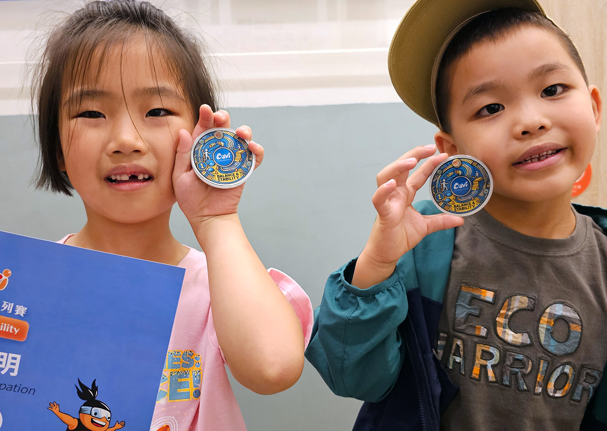 兩位兒童興奮展示 Oovi「穩定與平衡」挑戰賽的專屬圓形獎牌 (Medal),這份實體獎勵能強化孩子的內在動機,讓運動成為快樂且具備目標感的活動。