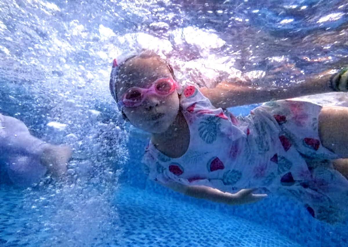 女童配戴粉紅泳鏡在水中自在潛水,展現極佳的閉氣控制與放鬆神情。這張高畫質水下照片證明 Oovi 課程能讓孩子真正享受游泳,建立強大的水性 (Water Confidence)。