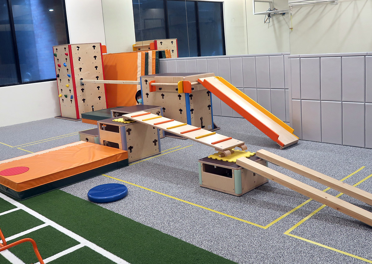 Oovi FMS 體能教室配置德國進口專業木製教具，包含攀岩牆、平衡木、滑梯與跳箱。這些高規格的模組化設備能組合成多變的循環訓練 (Circuit Training) 關卡，提供幼兒最安全且豐富的感覺統合探索環境。