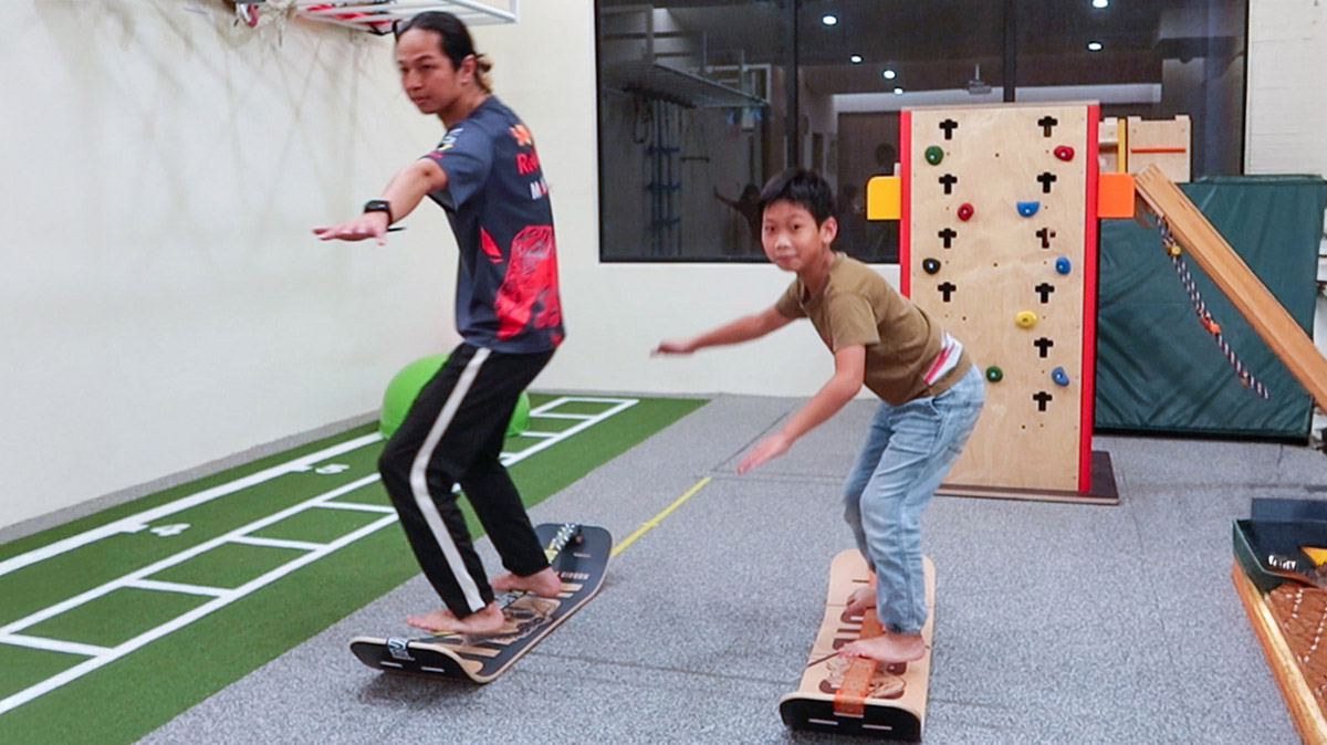 教練引導學童在室內教室練習平衡板，透過重心位移訓練強化核心肌群、專注力及手眼協調性。